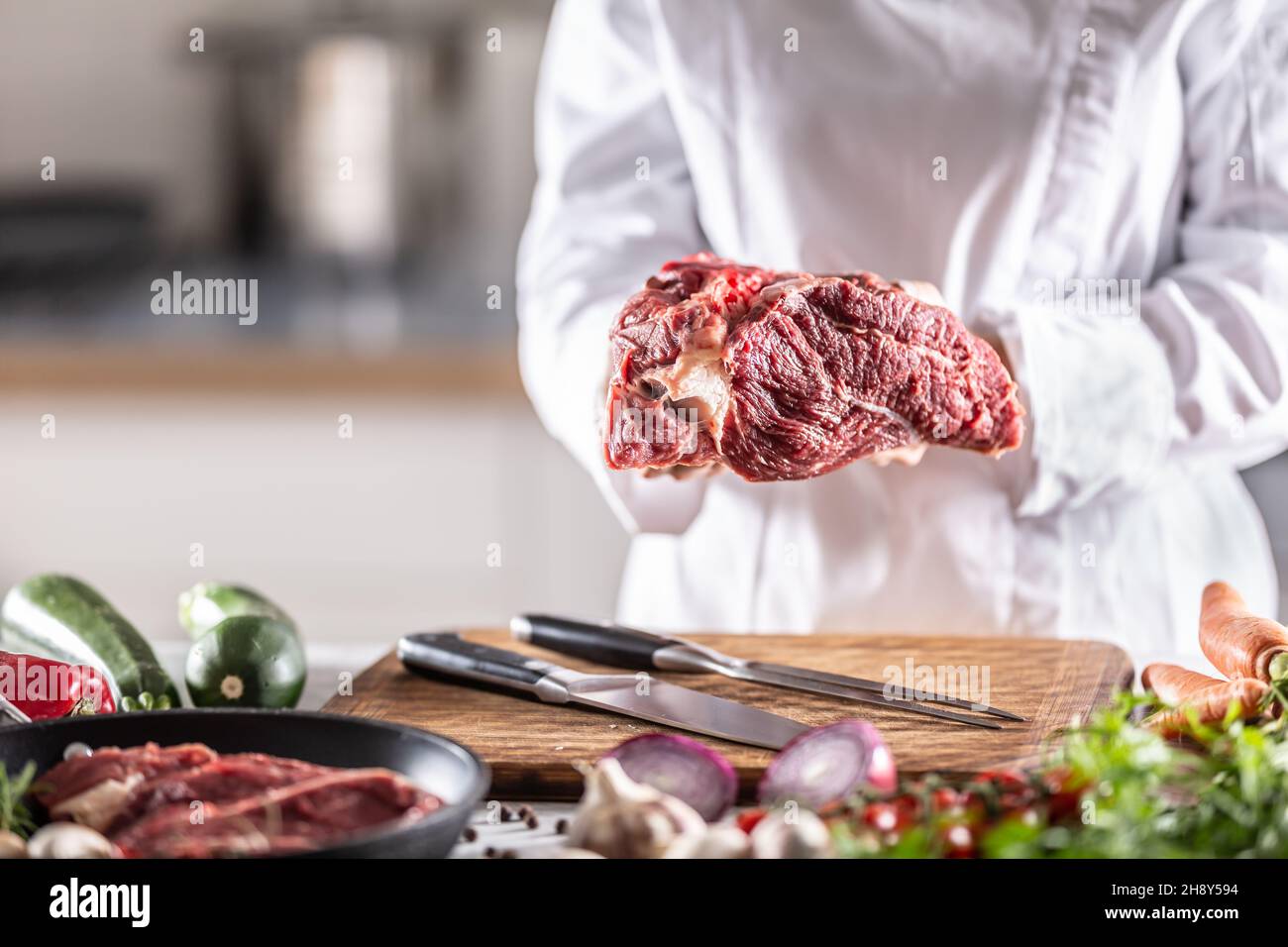 Dettaglio di uno chef che tiene in mano un grosso pezzo di carne rossa. Foto Stock