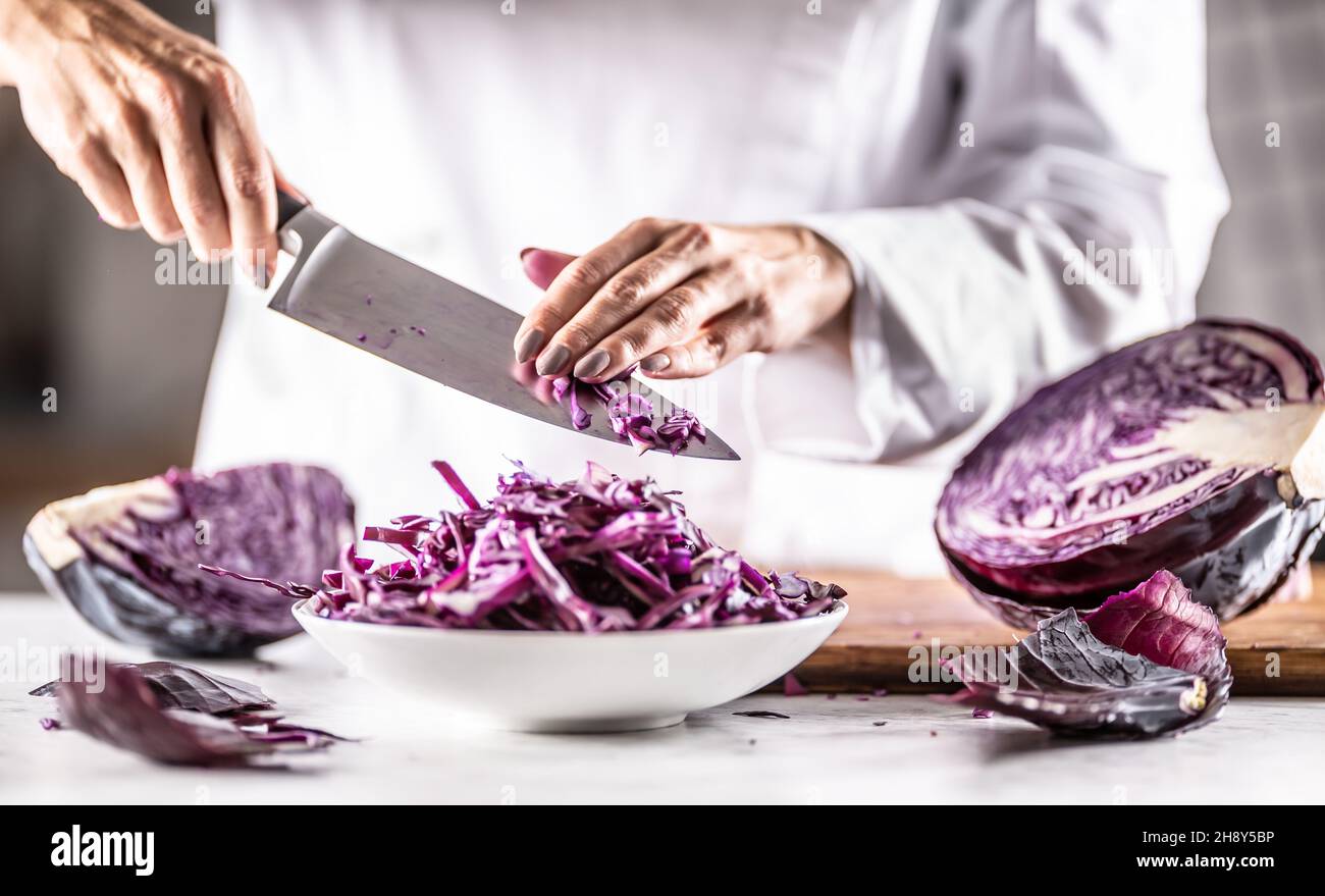 Lo chef prende i residui di cavolo rosso tagliato da un coltello in una ciotola. Foto Stock