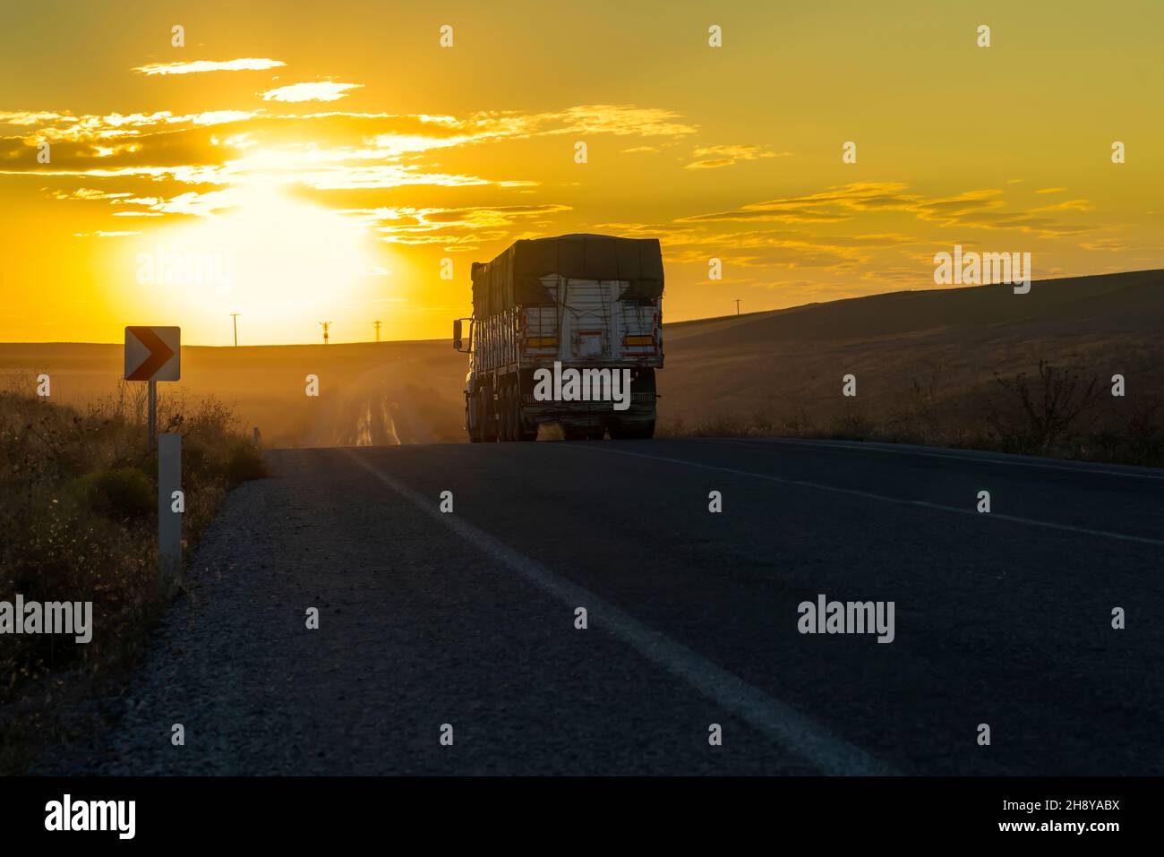 Vista posteriore del camion guida su una strada di campagna e il tramonto sullo sfondo. Foto Stock