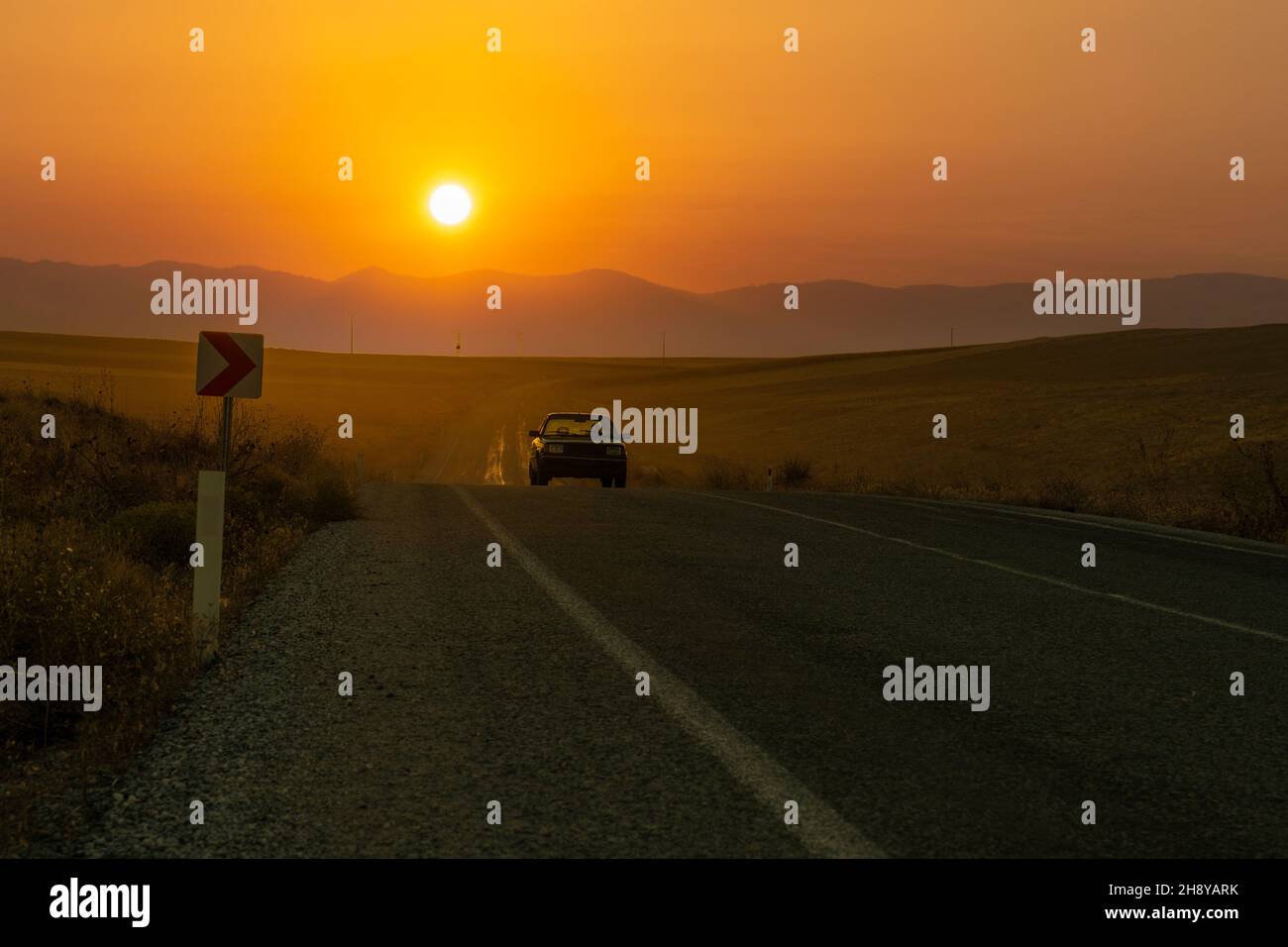 Eskisehir, Turchia - Settembre 12 2021: Auto vecchia guida su una strada di campagna e il tramonto sullo sfondo. Foto Stock