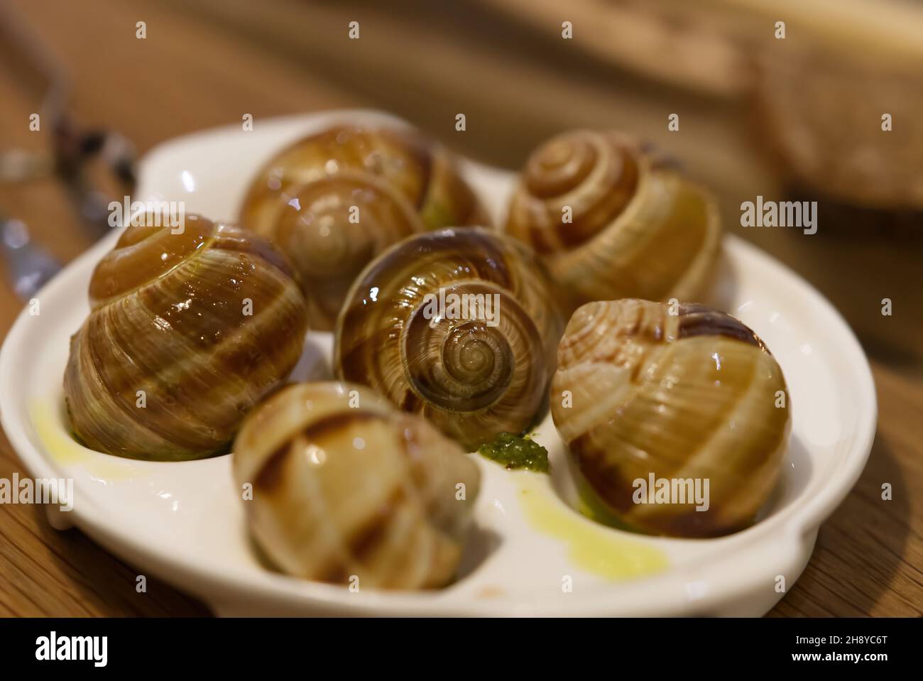 Helix Aspersa Muller piatto di lumaca in un ristorante. Lumache commestibili con burro e condimenti. Foto Stock