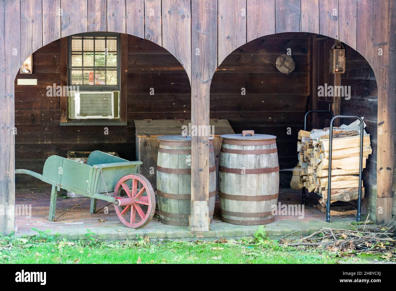 Tradizionale ambiente agricolo con una carenatura ruota, botti e billette di legno in un fienile di legno Foto Stock
