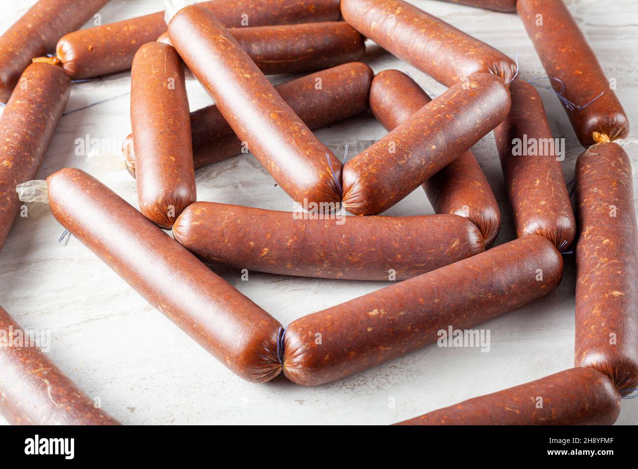 Closeup immagine isolata di corde di sucuk casalingo o salsiccia farcita in involucro e fatto in corde prima di asciugare. Consumo di carni rosse trasformate c Foto Stock