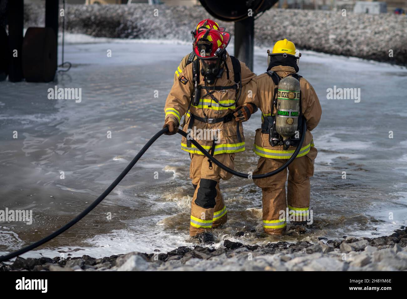 Gli Airmen degli Stati Uniti camminano braccio in braccio fuori da una fossa di fuoco dopo aver estinguito un fuoco vivo durante un'esercitazione della bandiera d'argento alla base dell'aeronautica militare di Tyndall, Florida, 4 novembre 2021. I vigili del fuoco sono addestrati mai a girare le loro spalle ad un fuoco che appena mettono fuori nel caso dovesse accendersi di nuovo, così uno mentre un vigile del fuoco cammina indietro, l'altro li conduce fuori. (STATI UNITI Air Force foto di Airman 1a classe Tiffany Prezzo) Foto Stock