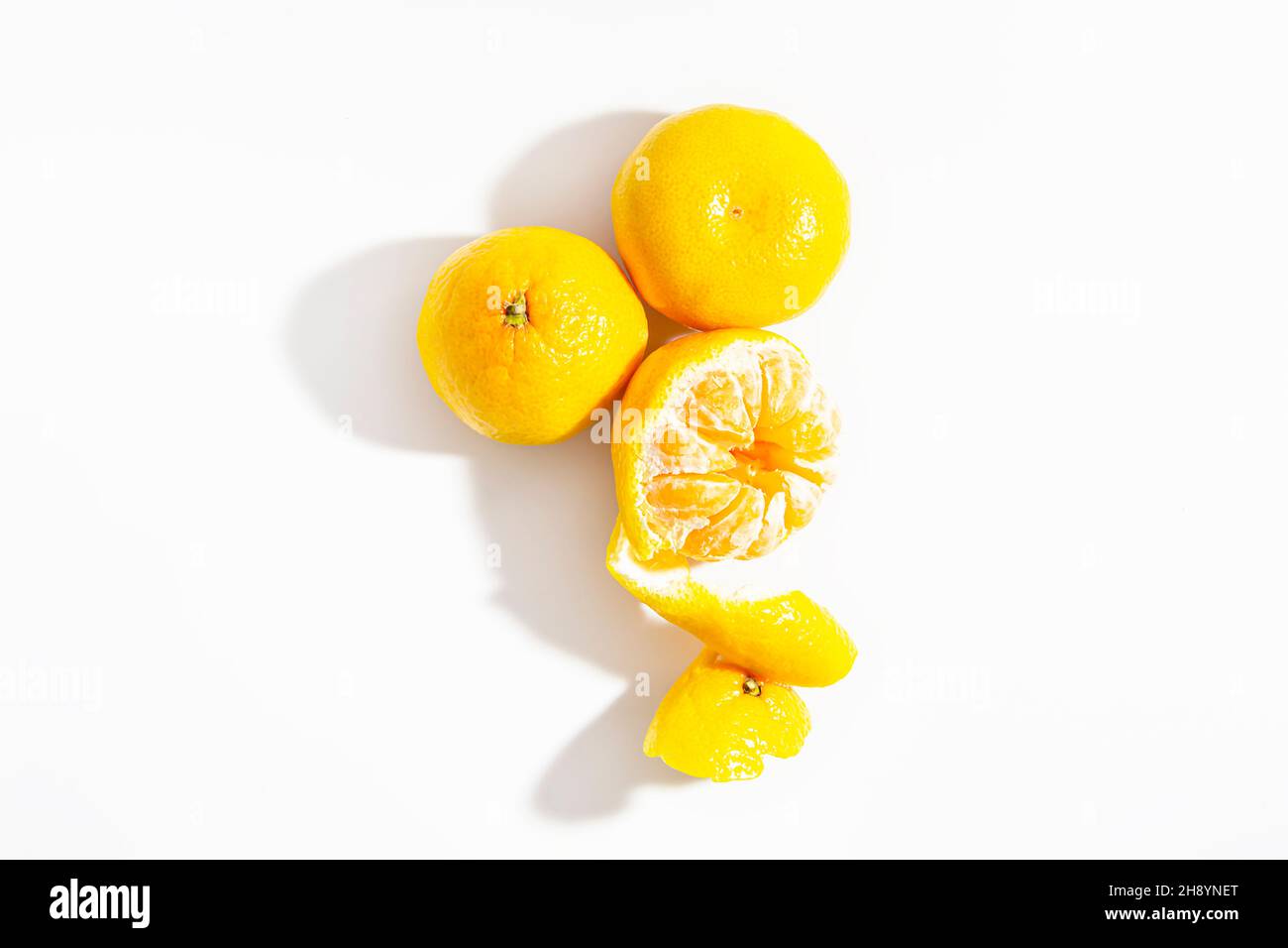 I tangerini semipacciati e i due tangerini interi si trovano su sfondo bianco. Isolare. Stile di vita. Primo piano. Vista dall'alto. Foto orizzontale. Foto di alta qualità Foto Stock