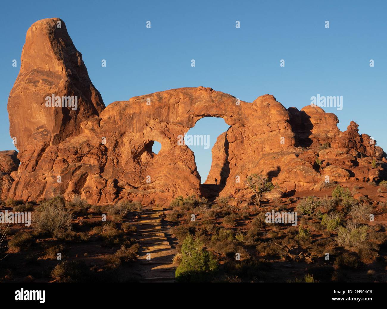 La silhouette di una persona in piedi nel Turret Arch National Park, Utah, all'alba. Foto Stock