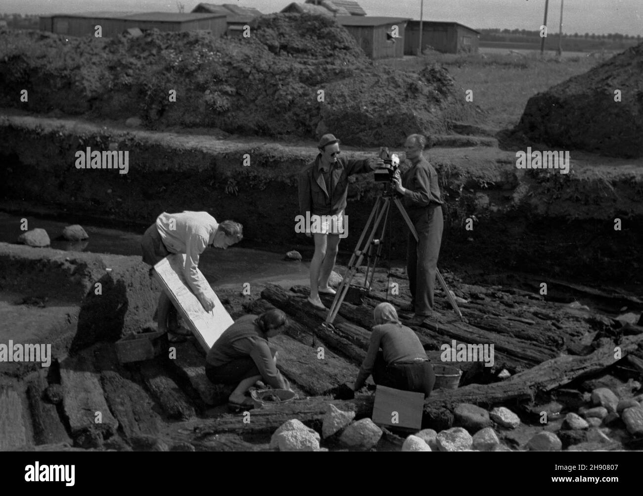 Biskupin, 1947. Prace archeologiczne na terenie drewnianej osady obronnej z prze³omu epoki br¹zu i ¿elaza (750-600 p.n.e. kultura ³u¿ycka) nad Jeziorem Biskupiñskim. NZ. Ekipa Przedsiêbiorstwa Pañstwowego Film Polski na terenie wykopalisk. bb/mgs PAP Dok³adny miesi¹c i dzieñ wydarzenia nieustalone. Biskupin, 1947. L'insediamento fortificato in legno fondato a turno dell'epoca del bronzo e del ferro (750-600 a.C., la cosiddetta cultura Luzyce). I lavori archeologici iniziarono nel 1933. Foto: Cameramen Polacco Film presso il sito di scavo. bb/mgs PAP Foto Stock