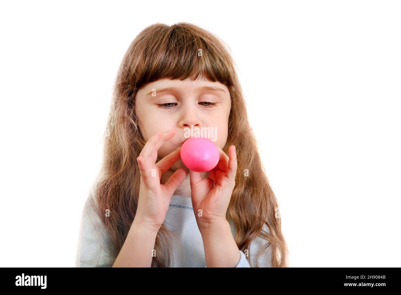Little Girl gonfia un palloncino rosa sullo sfondo bianco Foto Stock