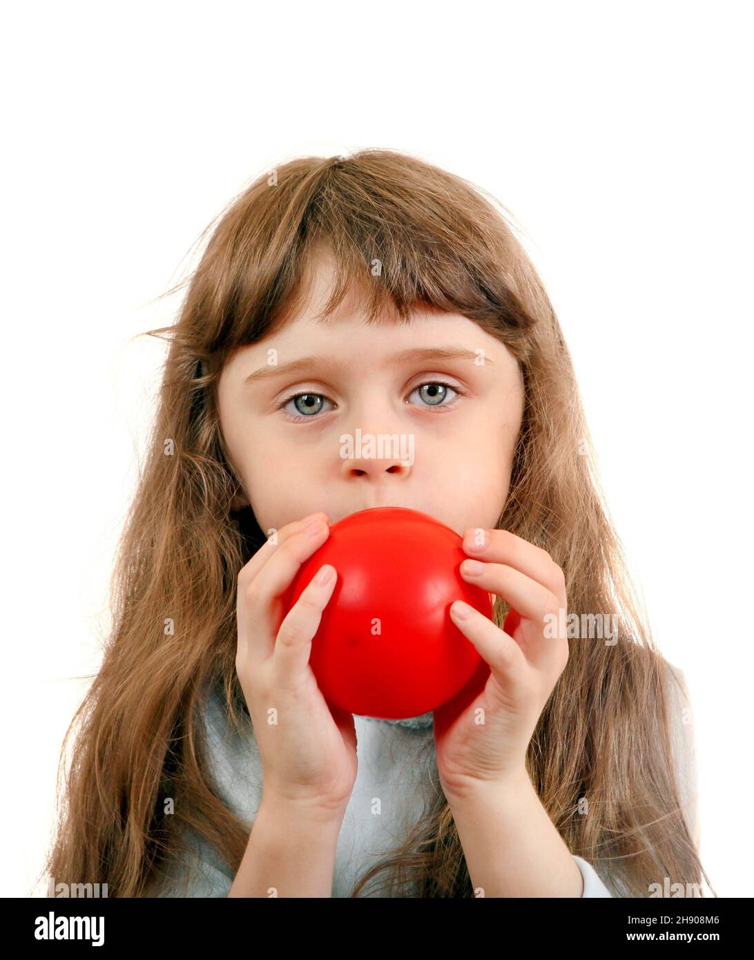 Little Girl gonfia un palloncino rosso sullo sfondo bianco Foto Stock