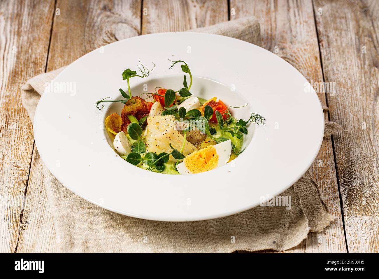 Primo piano insalata di pesce gourmet. Filetto di merluzzo, verdure, avocado e erbe fresche. Il ristorante serve. Piatto dello chef. Cibo sano e gustoso alla luce Foto Stock