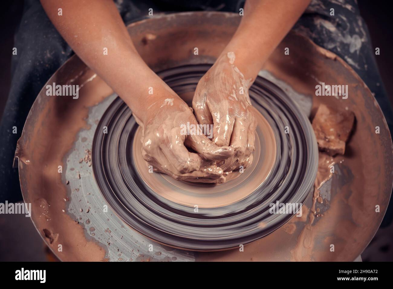 Mani del vasaio maestro e vaso di argilla sul primo piano della ruota del vasaio. Crock maestro. Ruota di vasaio attorcigliata. Foto Stock