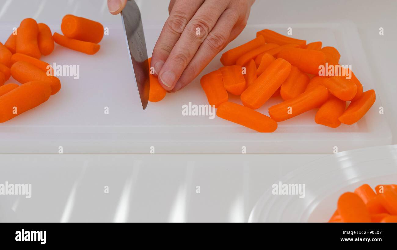 Donna taglia carota. Le carote fresche per bambini sbucciate organiche si  avvicinano sul tagliere del tavolo da cucina bianco Foto stock - Alamy