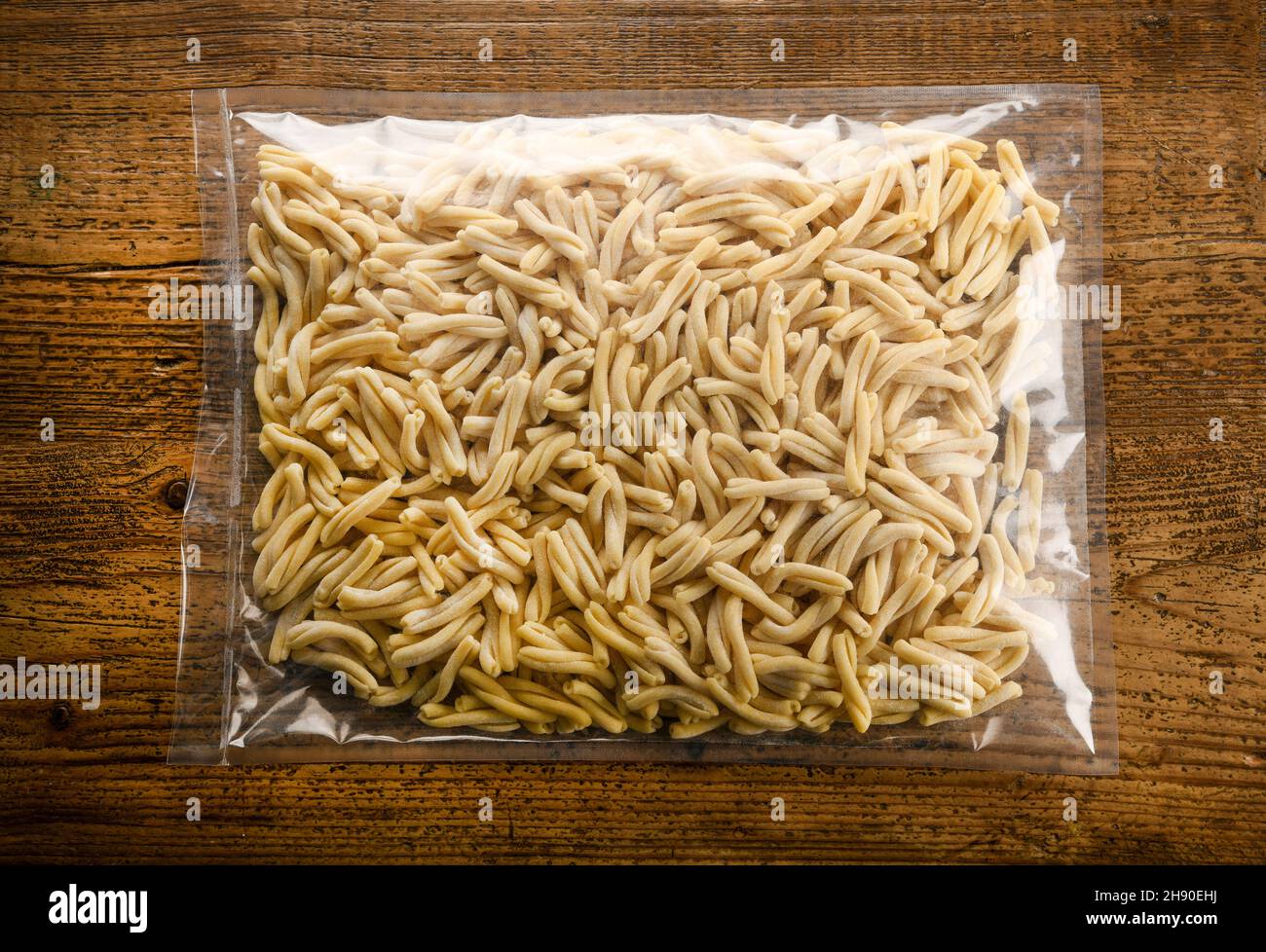 Pacchetto di pasta italiana secca Caseracce dalla Sicilia con noodle tradizionali intrecciate esposte su un tavolo di legno in vista dall'alto Foto Stock