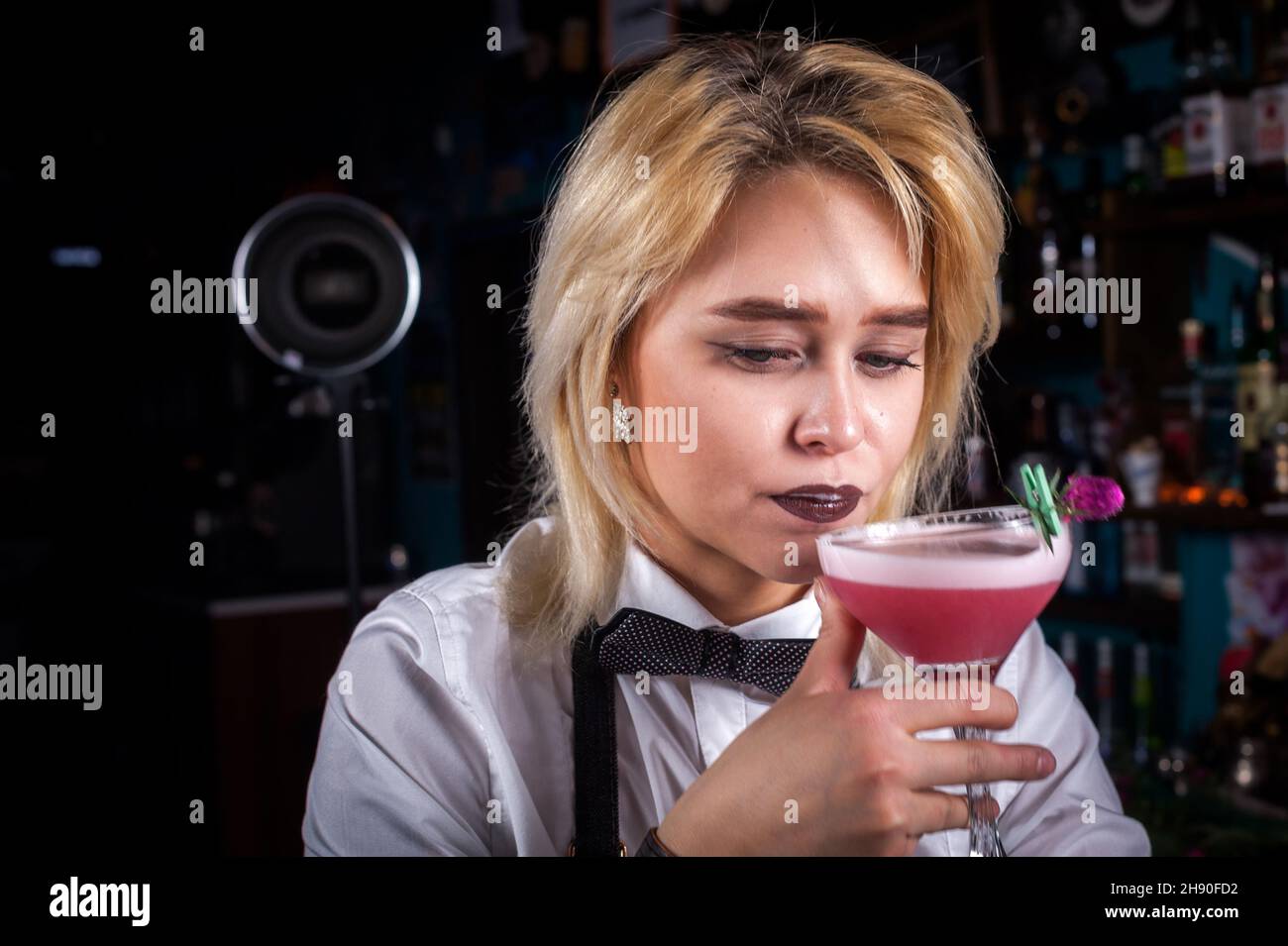 Il grazioso barman ragazza dimostra il processo di preparazione di un cocktail al banco del bar Foto Stock