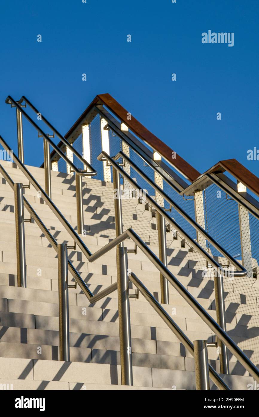 scalinata esterna in pietra o cemento moderna di scalini, scalini in pietra moderni e contemporanei con corrimano in legno e vetro rinforzato Foto Stock