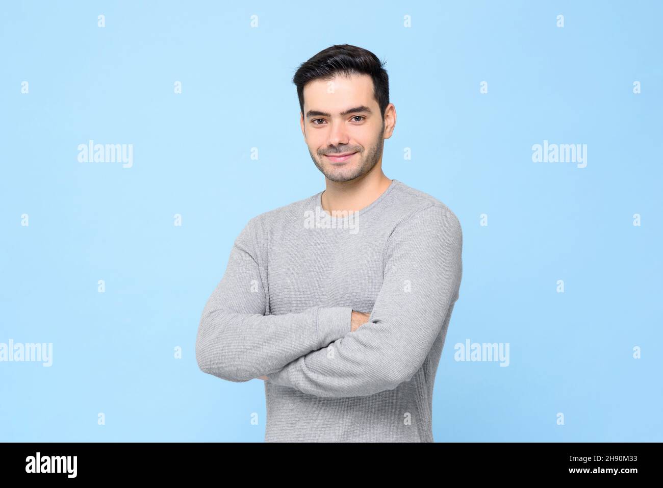 Vita ritratto di sorridente uomo simpatico in t-shirt grigio chiaro con braccia incrociate isolate in bakground studio blu chiaro Foto Stock
