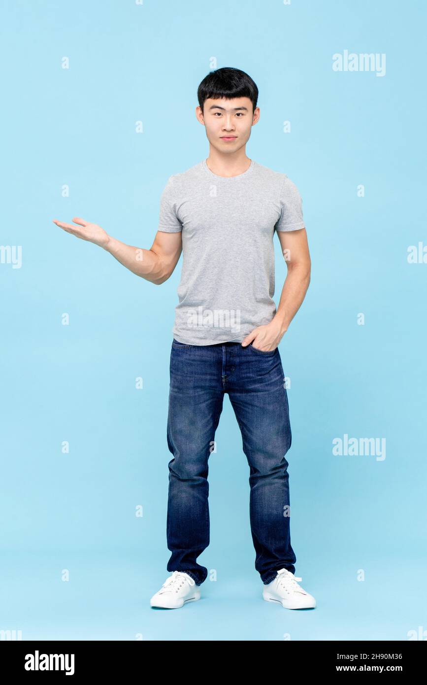 Ritratto a tutta lunghezza del giovane uomo asiatico con apertura a mano in isolato sfondo blu studio Foto Stock