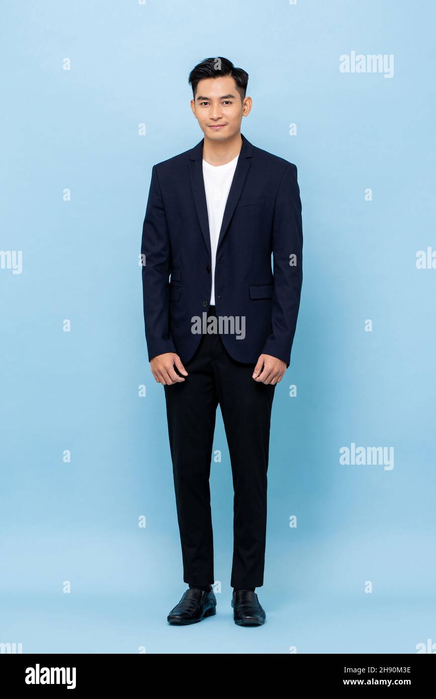 Felice sorridente giovane bel uomo d'affari del sud-est asiatico in piedi su sfondo chiaro blu studio Foto Stock