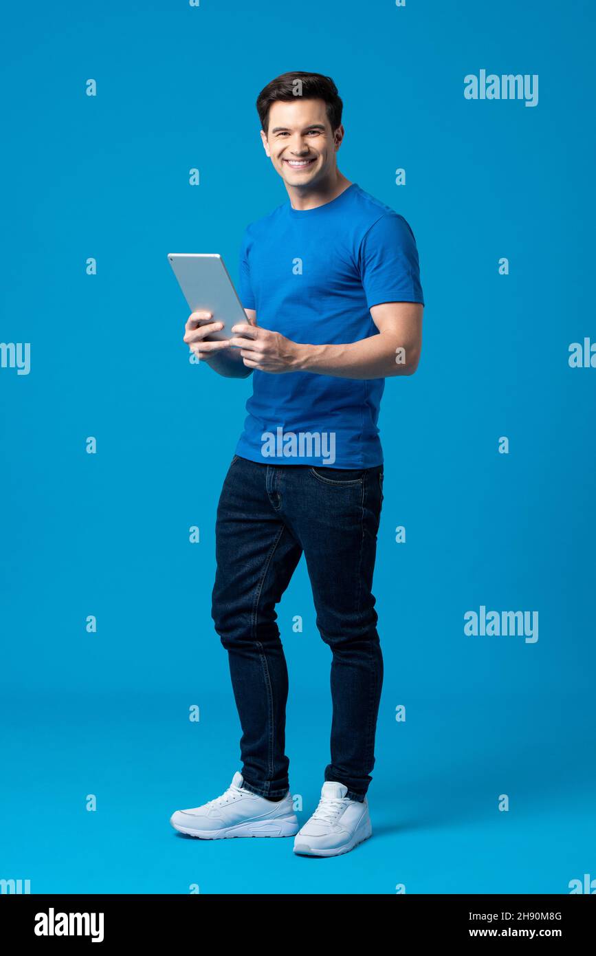 Ritratto completo del corpo di felice uomo caucasico americano tenendo computer tablet isolato su sfondo blu studio Foto Stock