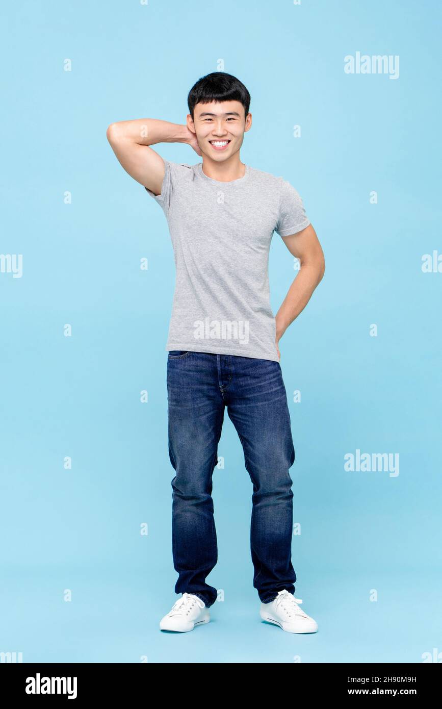 Ritratto di Faull lungo di sorridente giovane asiatico in piedi in blu chiaro isolato sfondo Foto Stock