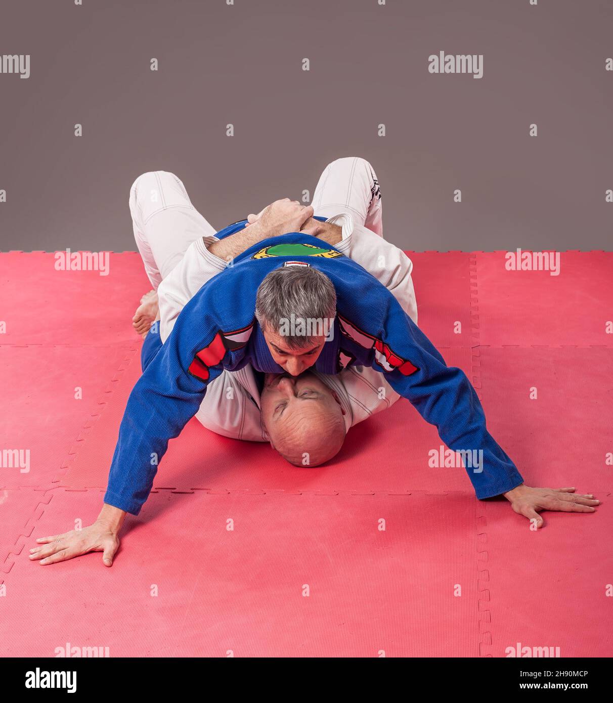 Kapap e il brasiliano jiu-jitsu istruttore in kimono tradizionale mostra posizione di montaggio a terra Foto Stock