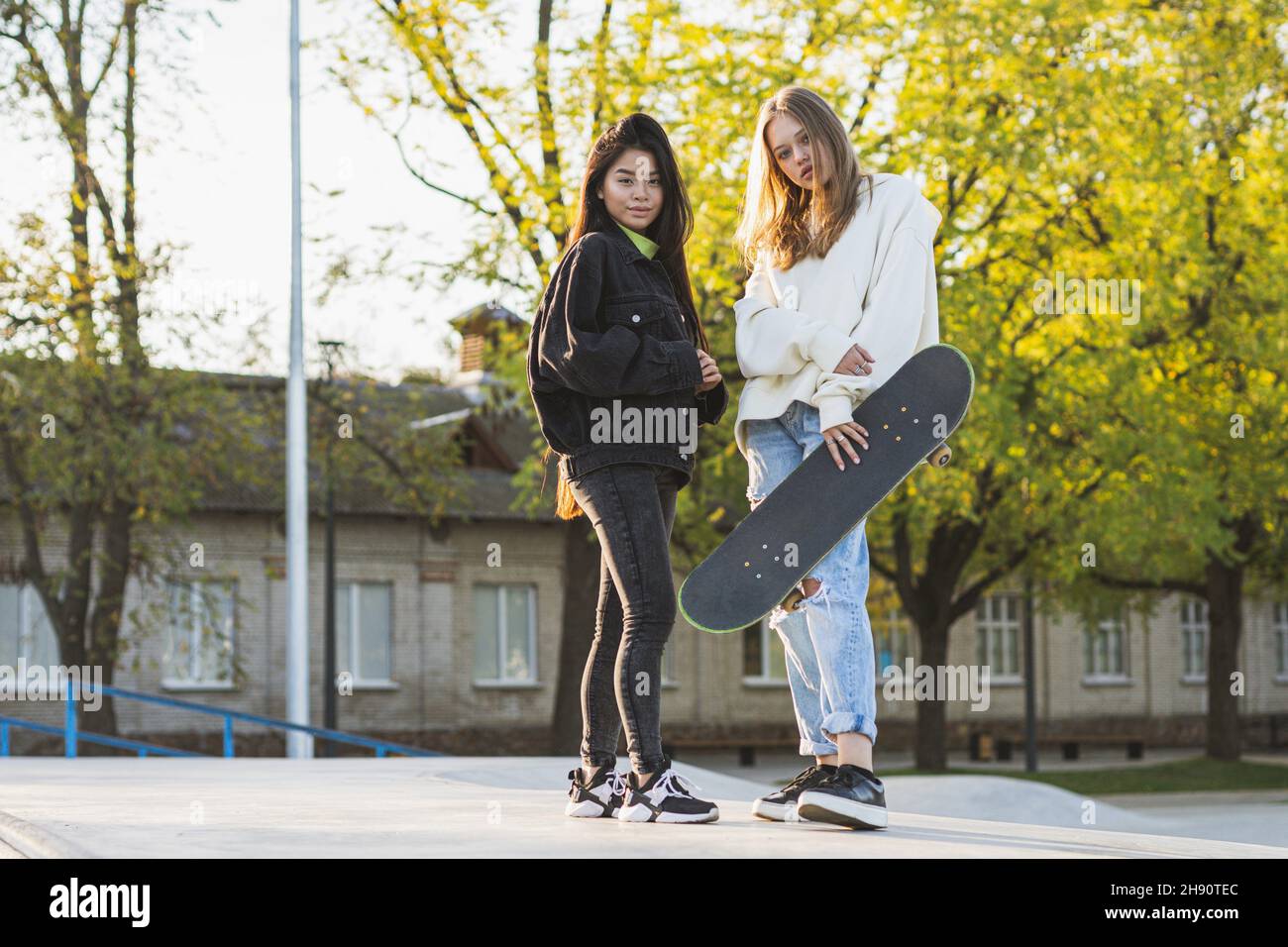 Gruppo multiculturale di giovani amici che si legano all'aperto e divertirsi - ragazzi alla moda e cool che si riuniscono al parco urbano skate. Foto Stock