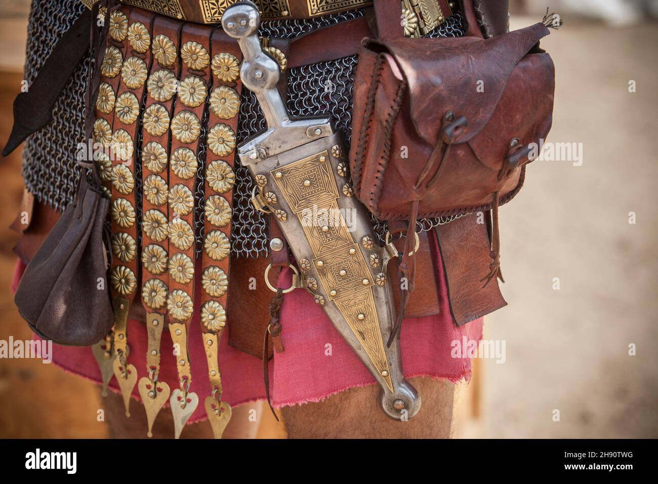 Centurion che cinge un pugio, un pugnale usato dai soldati romani come un braccio laterale. Rievocazione storica. Foto Stock