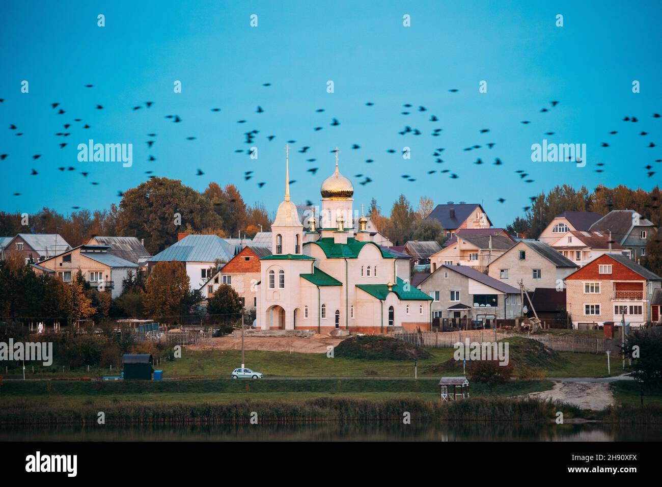 Glubokoye, regione di Vitebsk, Bielorussia. Flock of Birds si affaccia sulla Chiesa Basiliana di San Pietro e Paolo e Monastero, settore residenziale privato da Foto Stock