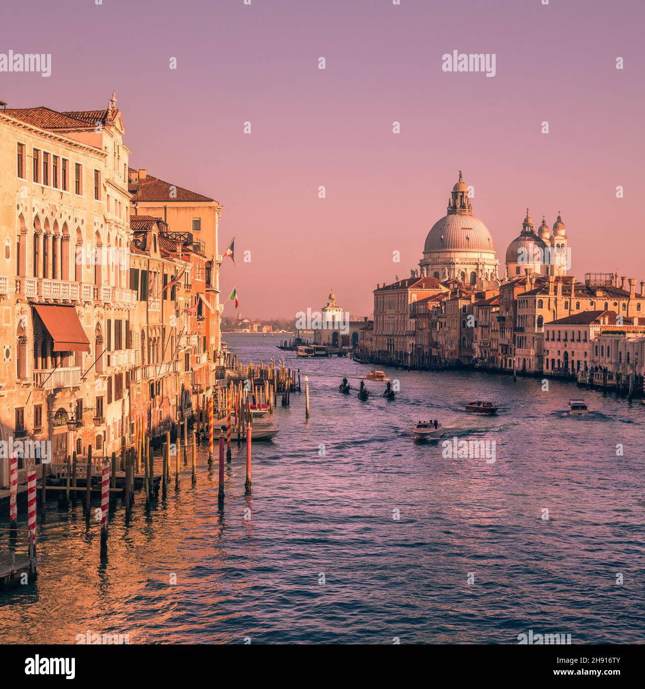 Barche nel canale con la famosa Basilica di Santa Maria della Salute sullo sfondo al tramonto Foto Stock