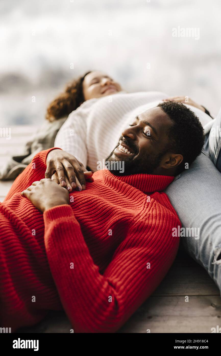 Coppia eterosessuale sorridente che si rilassa sul molo Foto Stock