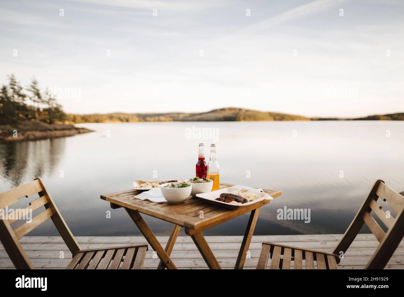Il cibo è organizzato sul tavolo vicino al lago contro il cielo Foto Stock