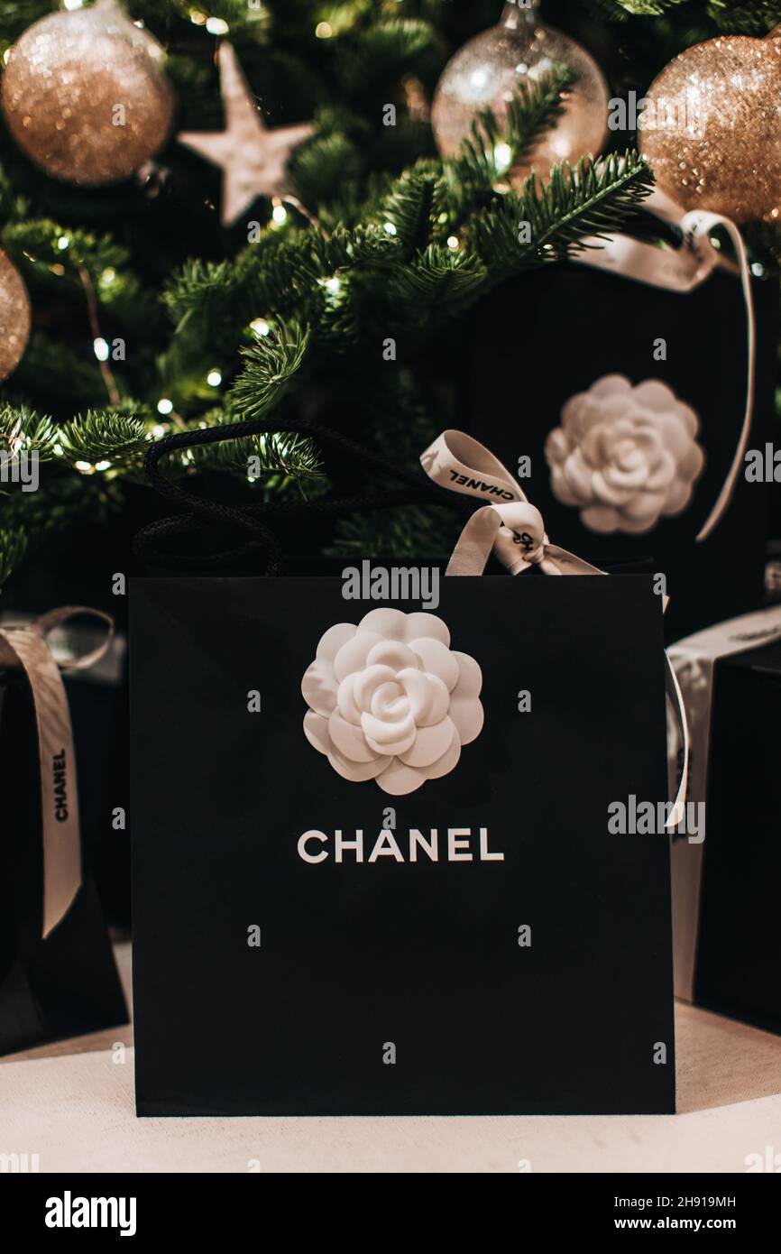 Borsa regalo per le feste Chanel con nastri bianchi sotto l'albero di Natale. Regali di lusso per l'anno nuovo Foto Stock