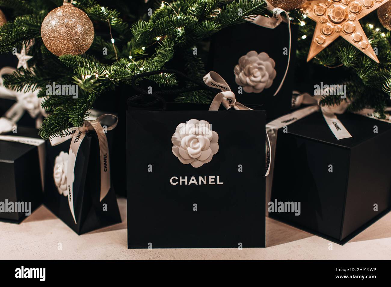 Borsa regalo per le feste Chanel con nastri bianchi sotto l'albero di Natale. Regali di lusso per l'anno nuovo Foto Stock