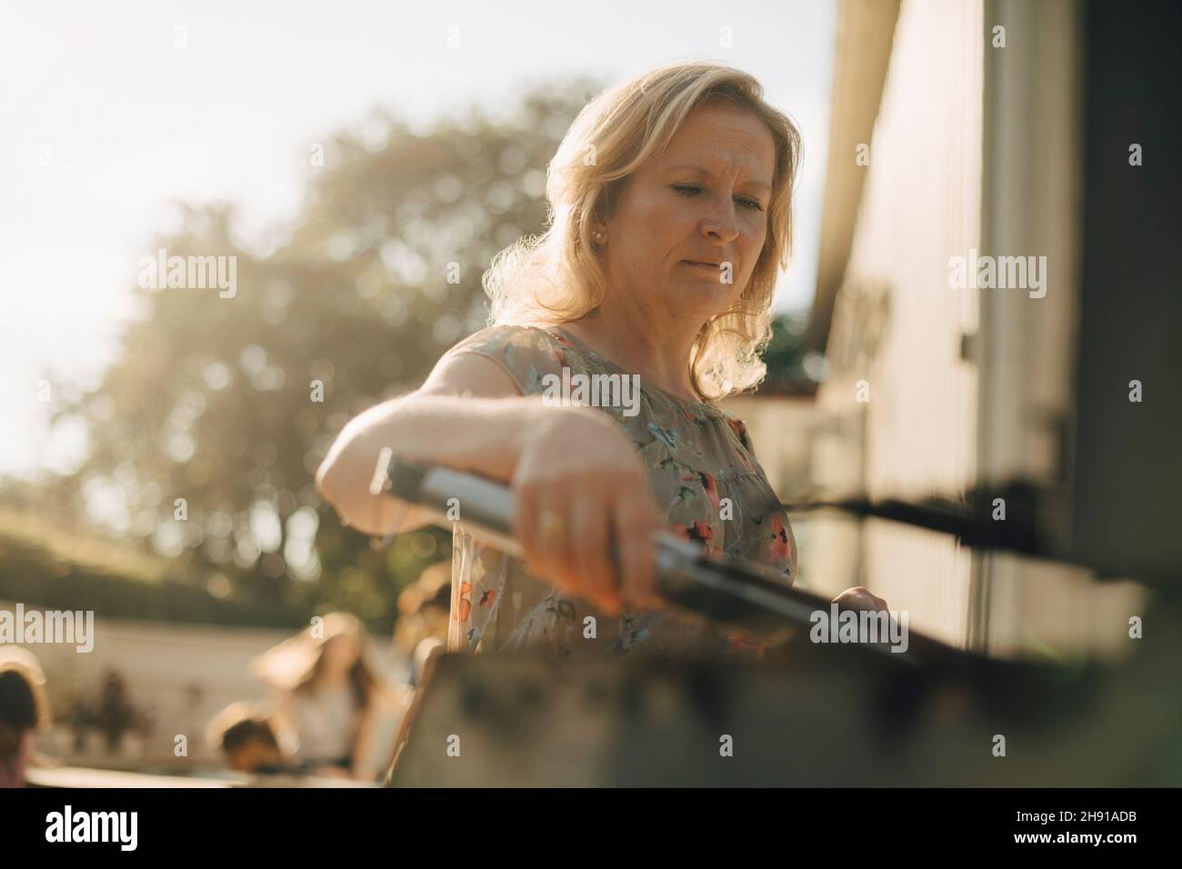 Donna matura che prepara il cibo sul barbecue grill durante la cena Foto Stock