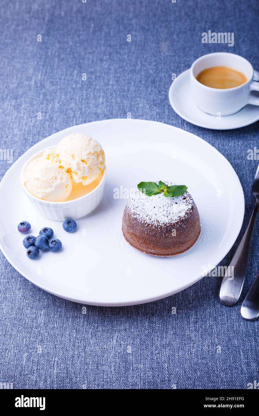 Torta di lava - torta al cioccolato fondente con gelato alla vaniglia, mirtilli, menta e caffè. Dolci francesi tradizionali. Primo piano. Foto Stock