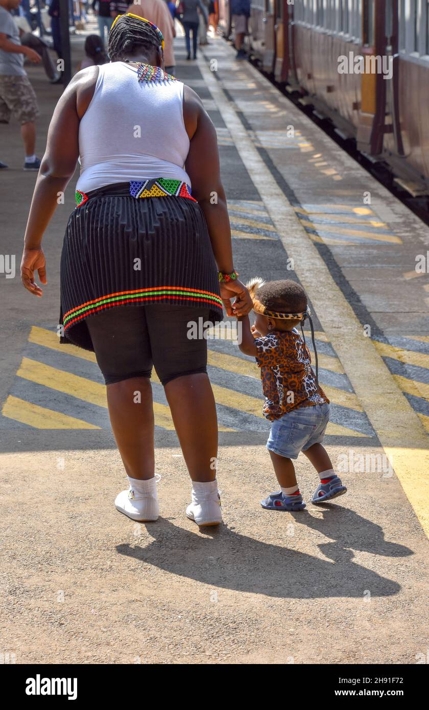 Una madre che tiene le mani con suo figlio bambino in abito zulu a Pretoria Sud africa simboleggia la forza, il futuro e la speranza di una nuova generazione di leade Foto Stock