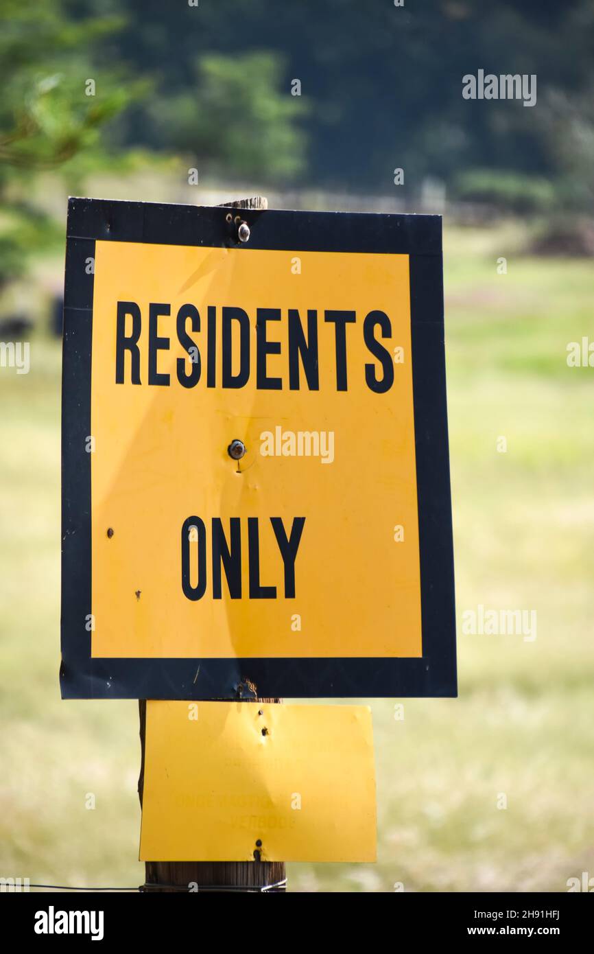 Un segno giallo brillante che dice residenti solo con un bordo spesso nero sullo sfondo di un prato che limita l'accesso a terzi alla zona Foto Stock