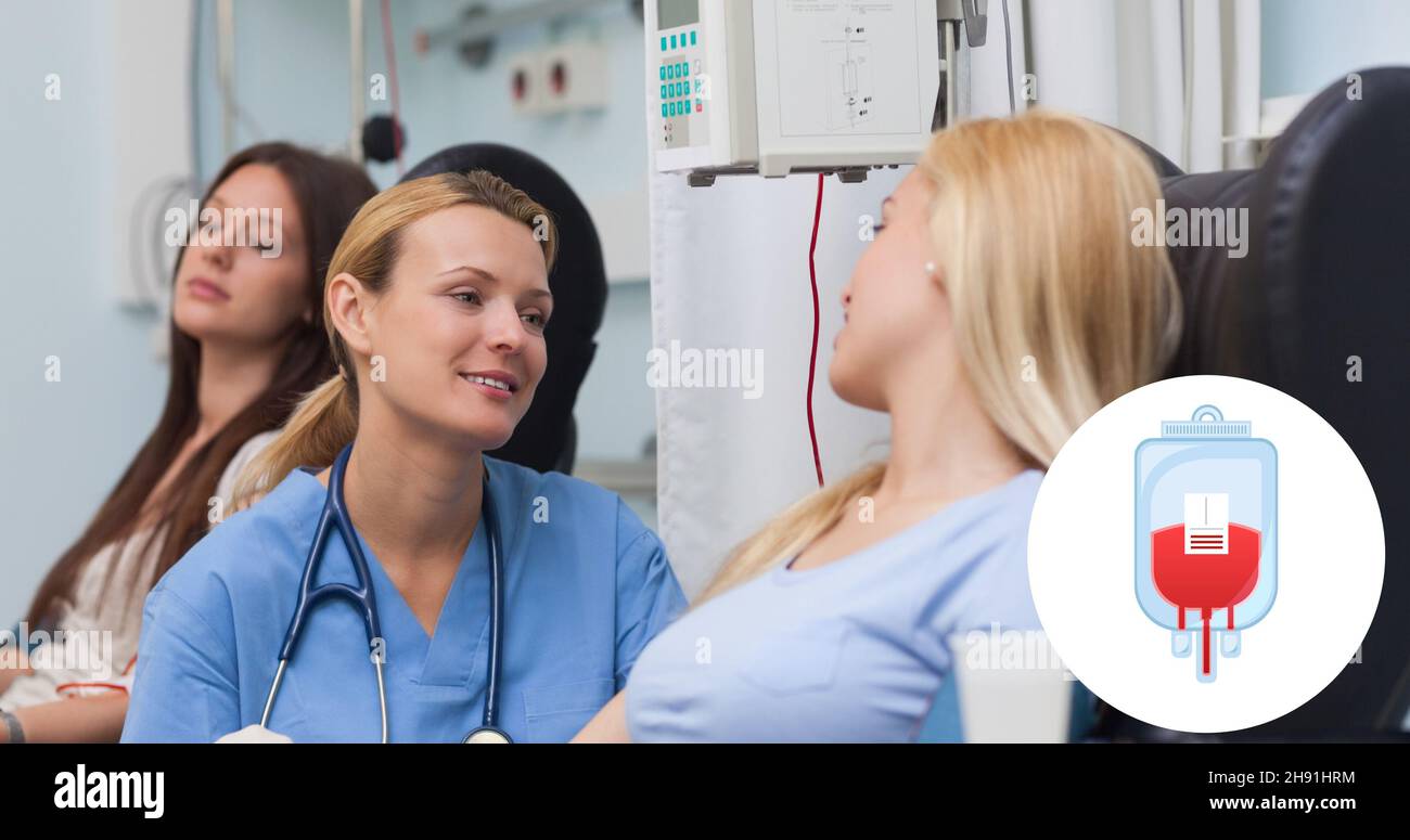 Medico sorridente che guarda il donatore seduto sulla sedia durante la donazione di sangue in ospedale Foto Stock