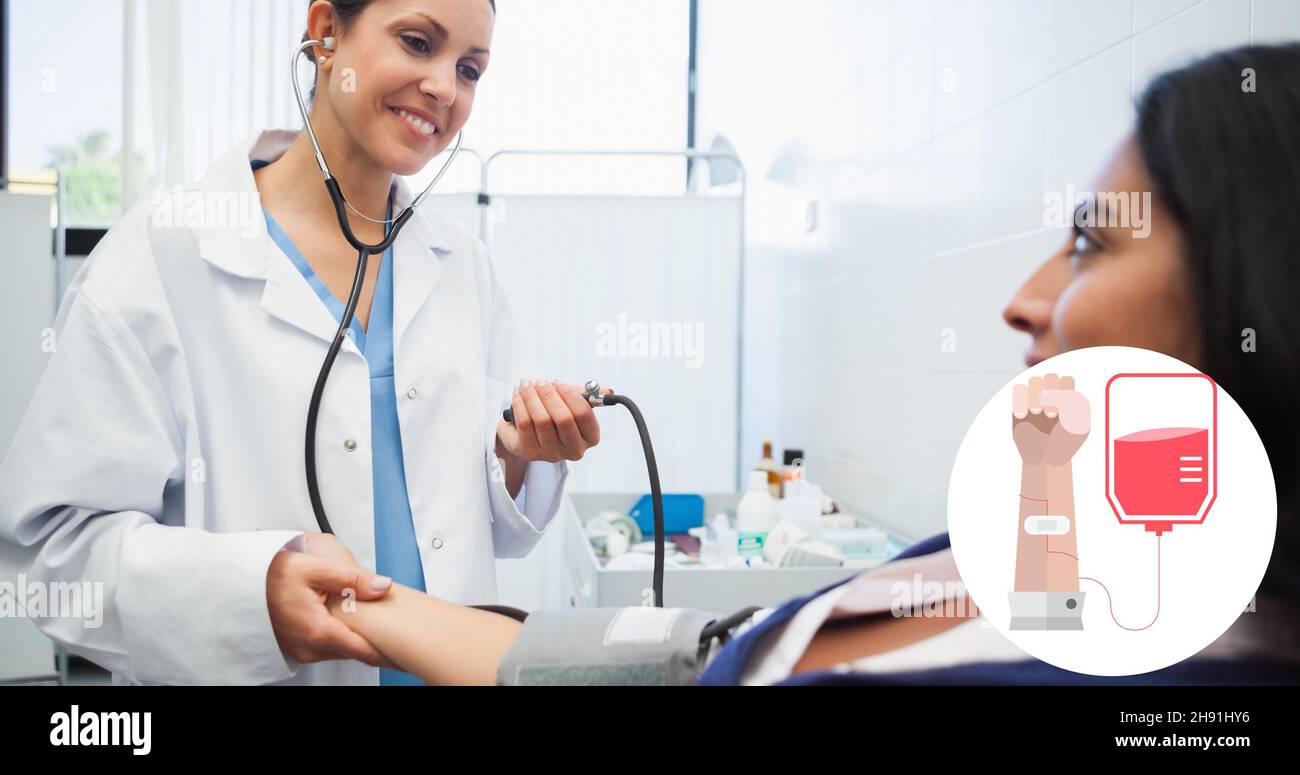 Medico sorridente che controlla la pressione sanguigna della paziente in ospedale con il simbolo della donazione di sangue Foto Stock
