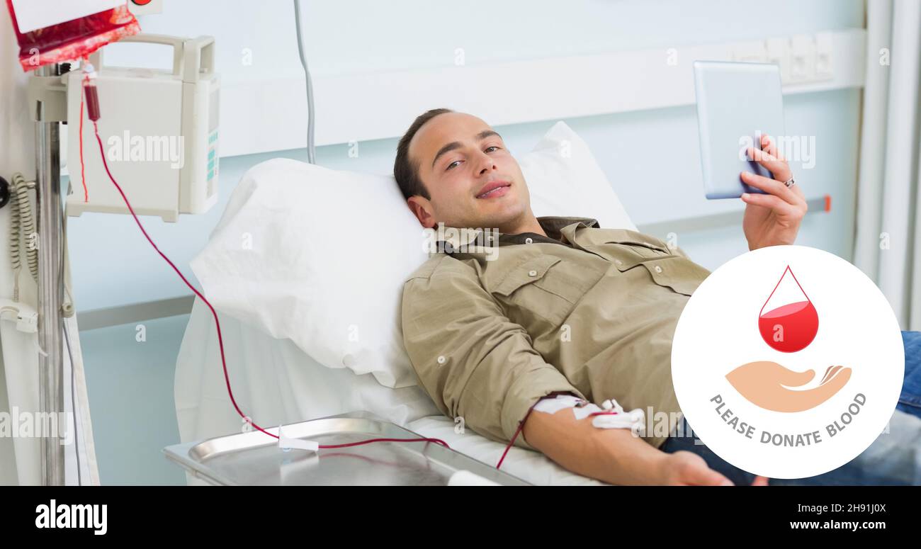 Ritratto di donatore maschile sorridente che si trova con tavoletta digitale a letto durante la donazione di sangue in ospedale Foto Stock