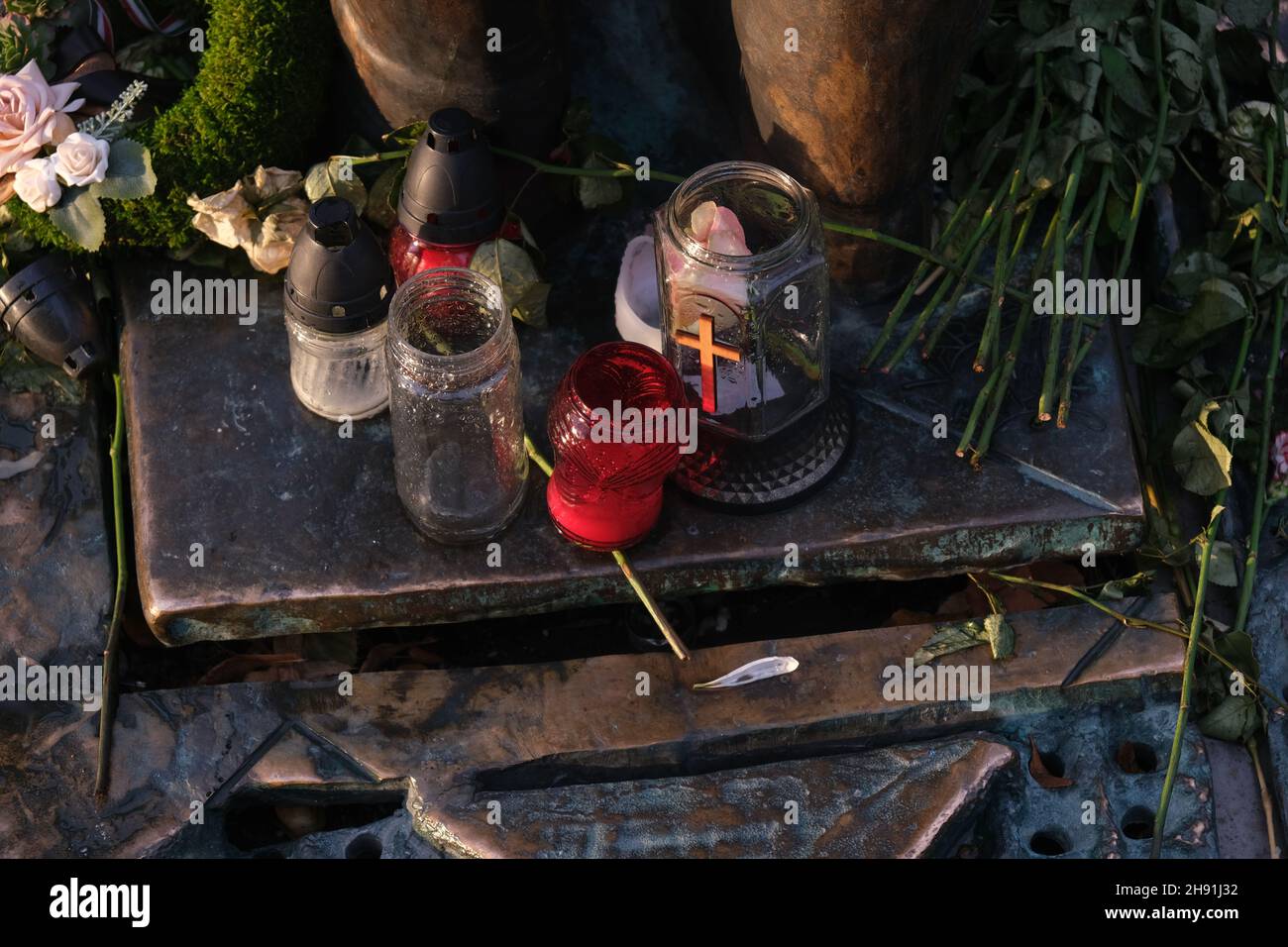 Vasi di vetro con croce cristiana e fiori al memoriale. Foto Stock