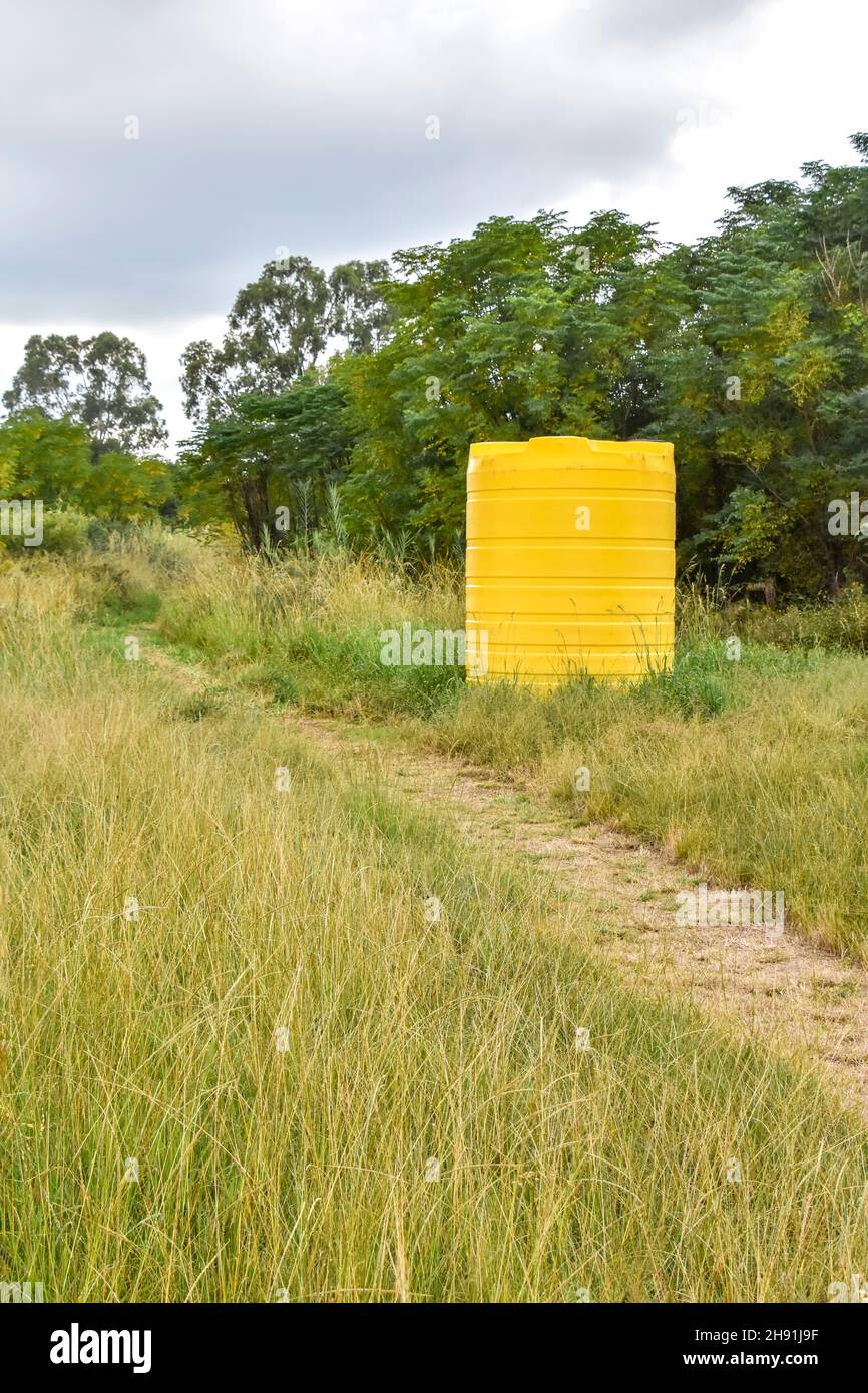 Un grande contenitore giallo di dimensioni industriali contenente migliaia di litri di acqua in piedi in una fattoria vicino ad un campo in Sudafrica utilizzato per immagazzinare l'acqua Foto Stock