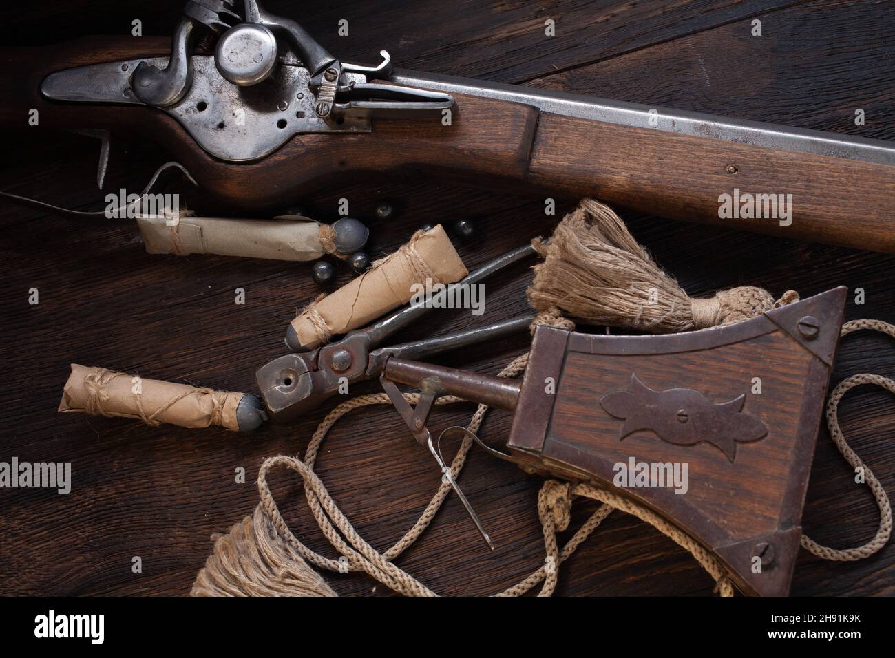antico muschio di flintlock del xvii secolo con fiasca di polvere e pallottole a led su ponte di legno. Foto Stock