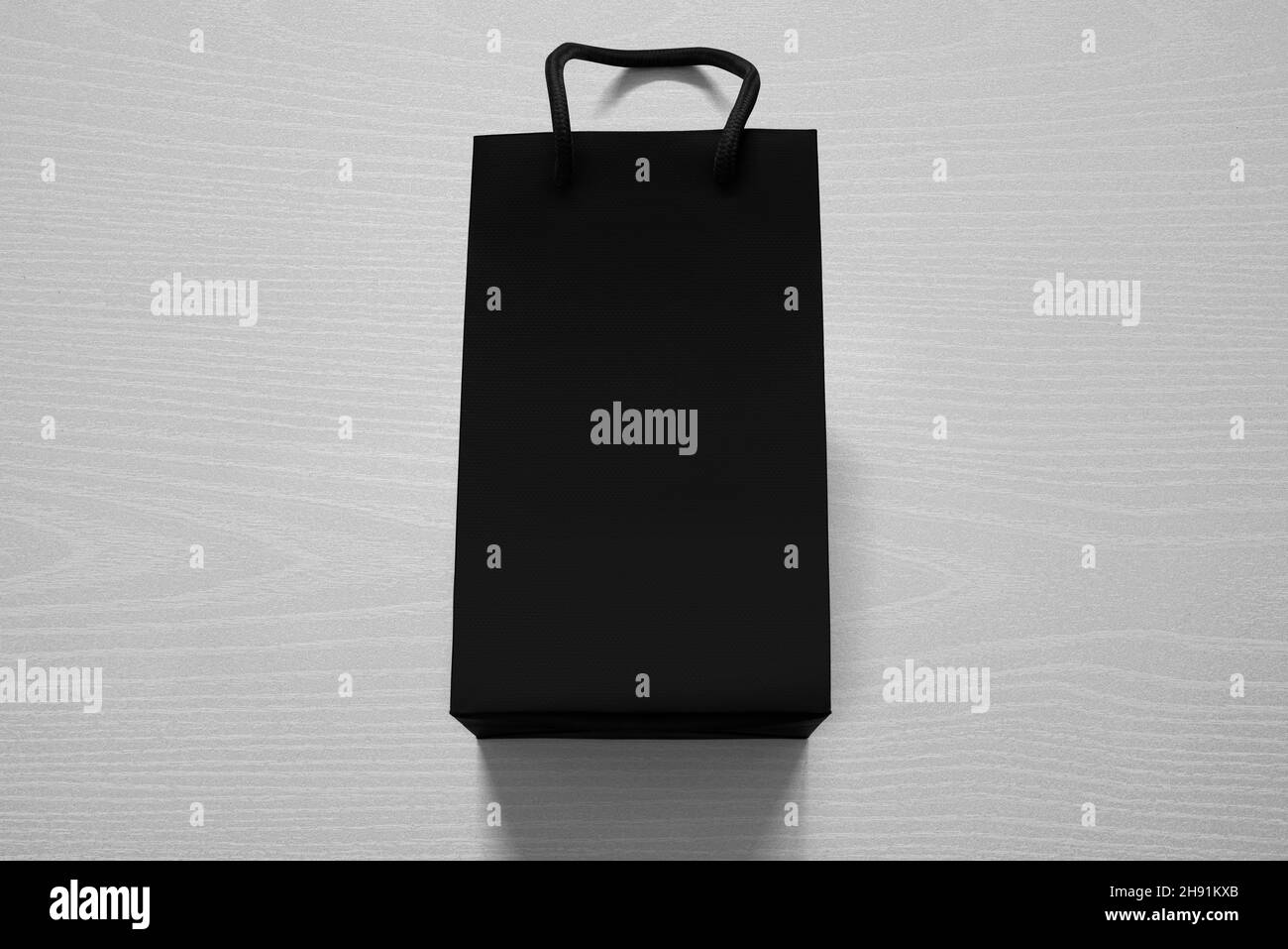 Borsa shopping di lusso nera opaca contro il legno bianco dall'alto Foto Stock