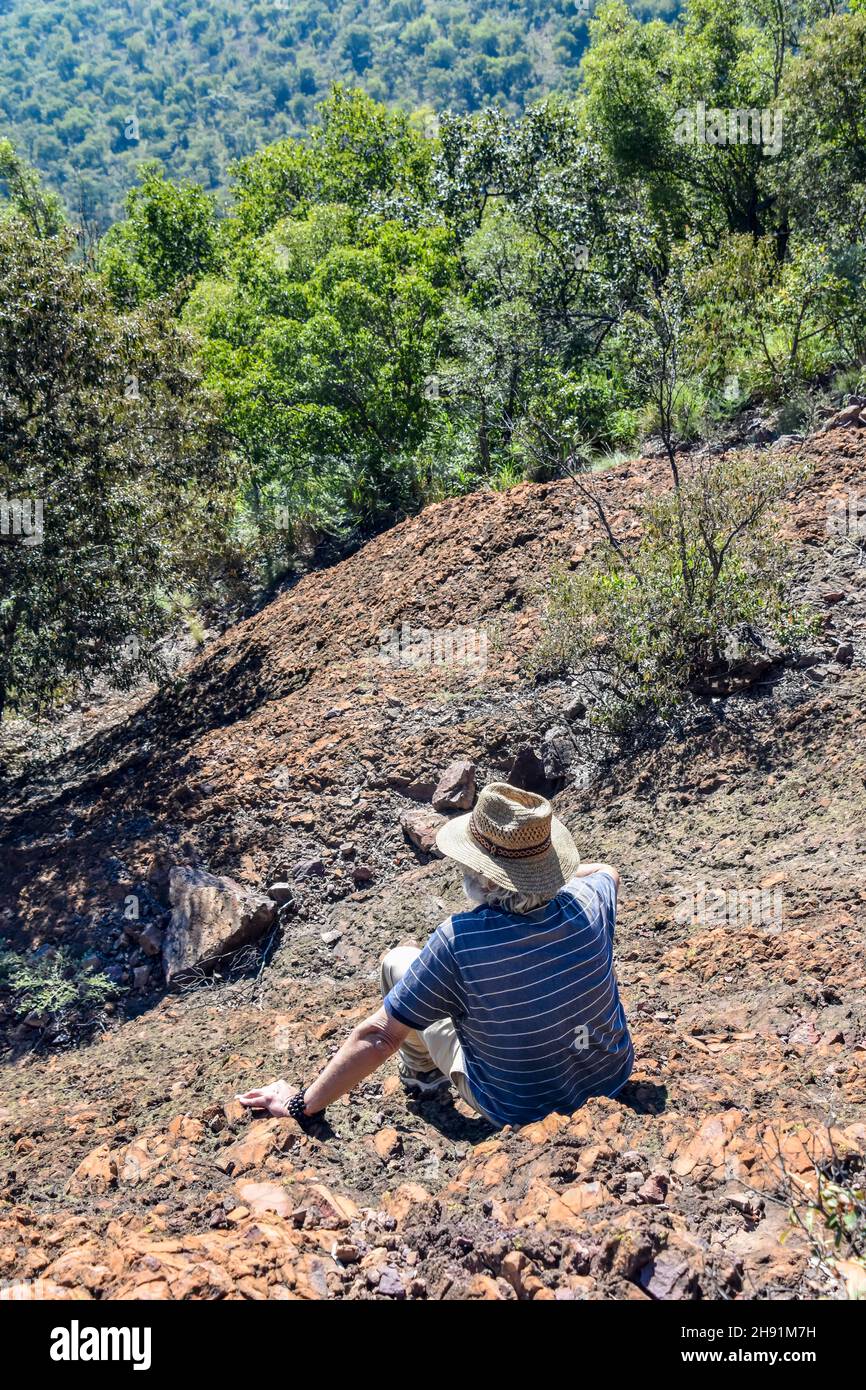 Un contadino con un cappello da cowboy che osserva la zona tenendo le mani sulle rocce che si trovano sulle colline vicino al fiume Wilge in prossimità di Bronkhorstspruit Foto Stock