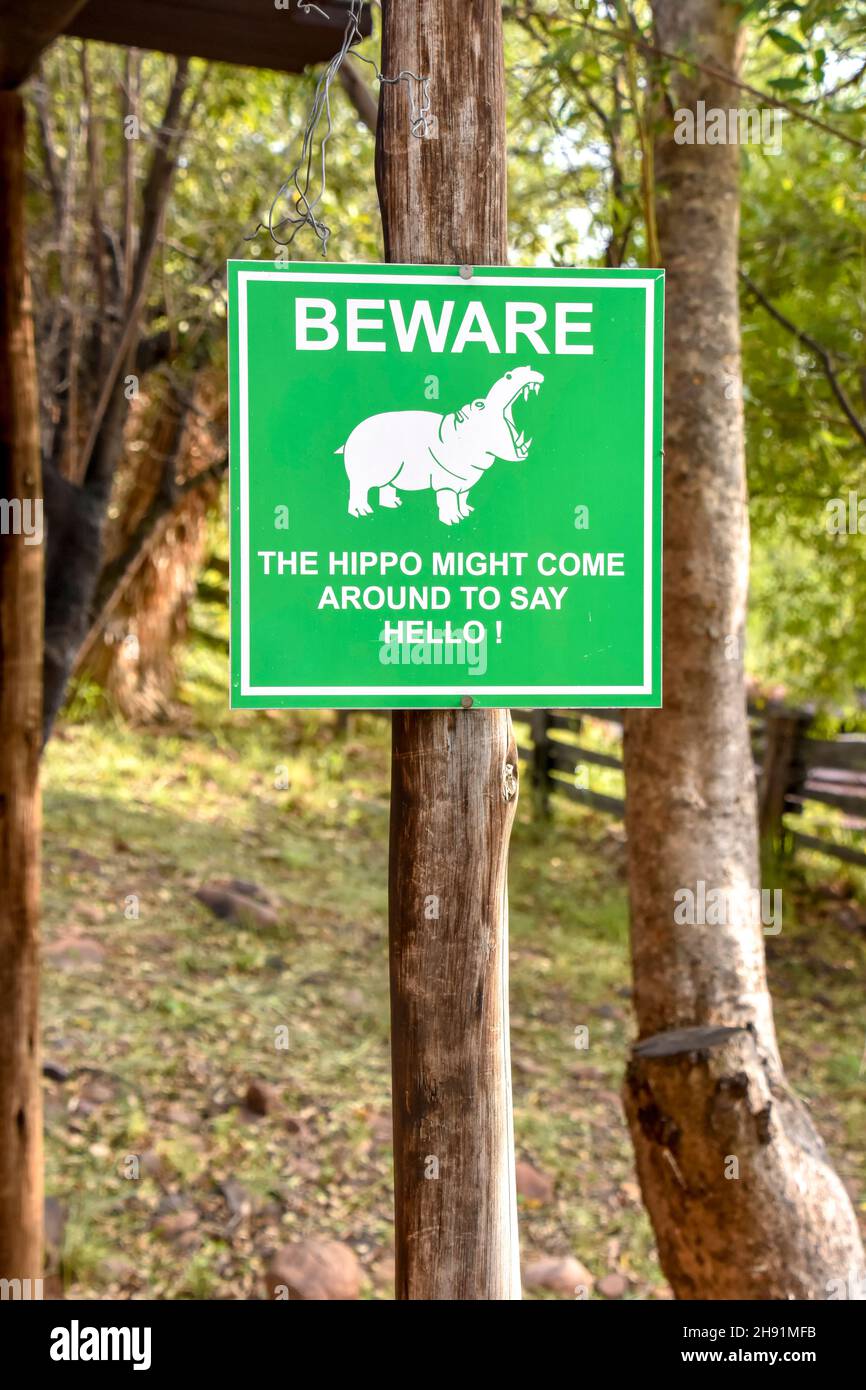 Un cartello verde che avverte la gente che dice di essere consapevole che l'ippopotamo può venire intorno e dire ciao usato in un campo per gli escursionisti in Sudafrica a Wilge River in Foto Stock