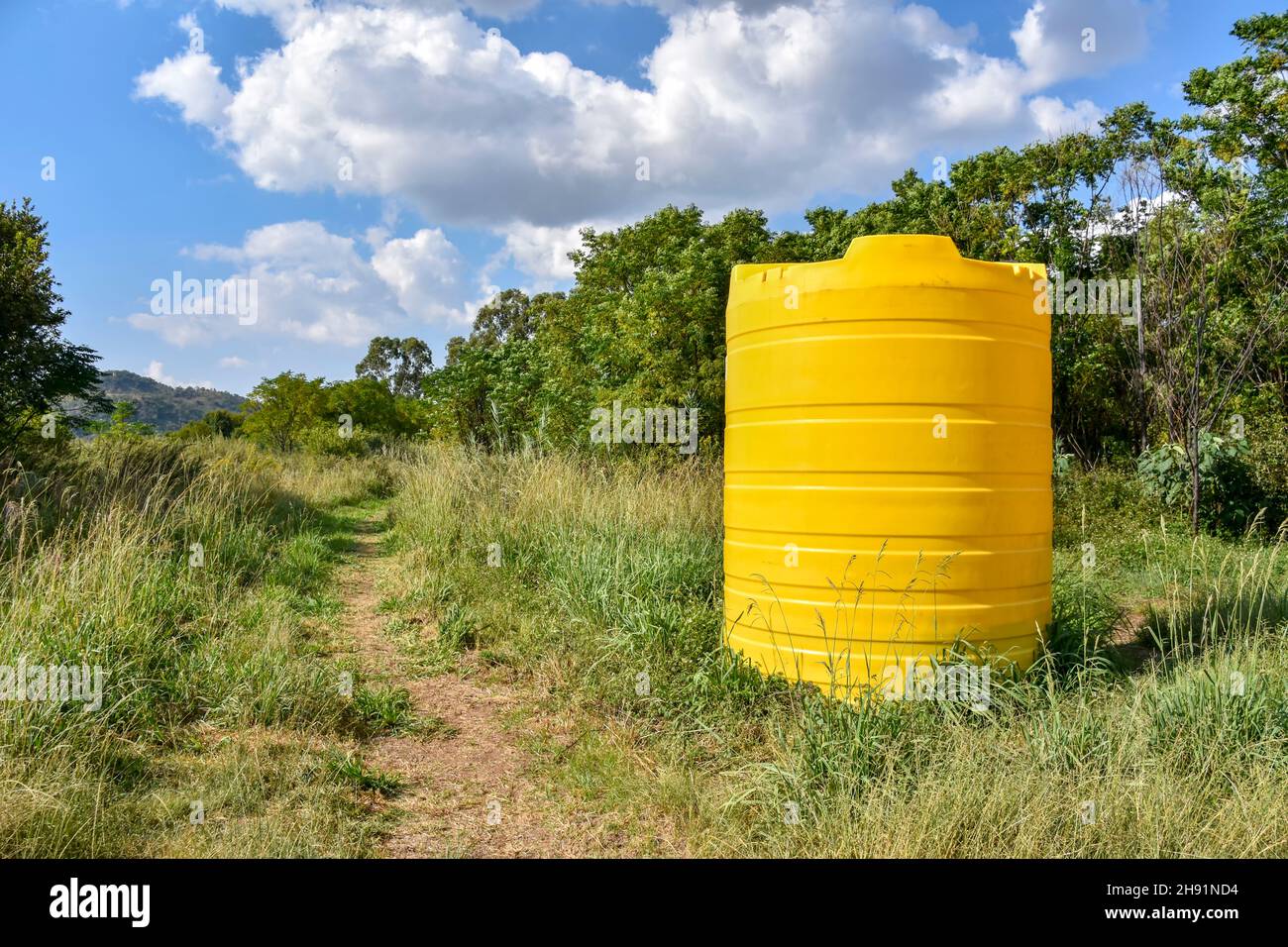 Un grande contenitore giallo di dimensioni industriali contenente migliaia di litri di acqua in piedi in una fattoria vicino ad un campo in Sudafrica utilizzato per immagazzinare l'acqua Foto Stock