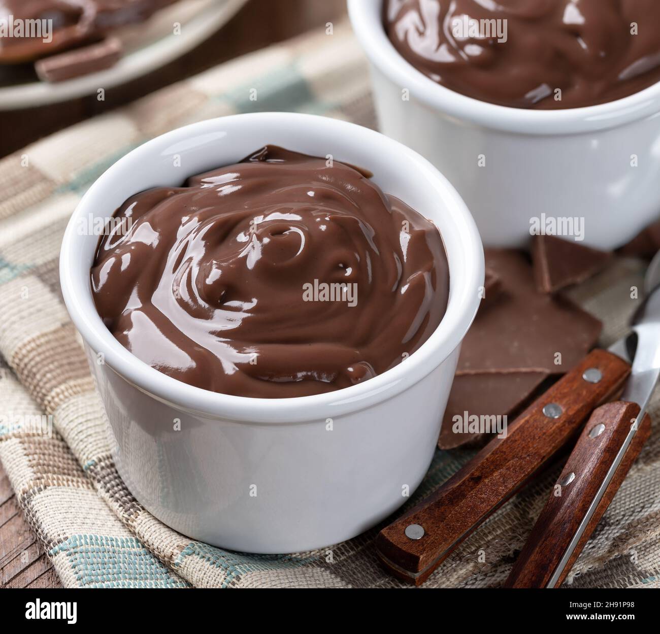 Primo piano di budino di cioccolato cremoso in una tazza bianca su un tovagliolo di stoffa Foto Stock