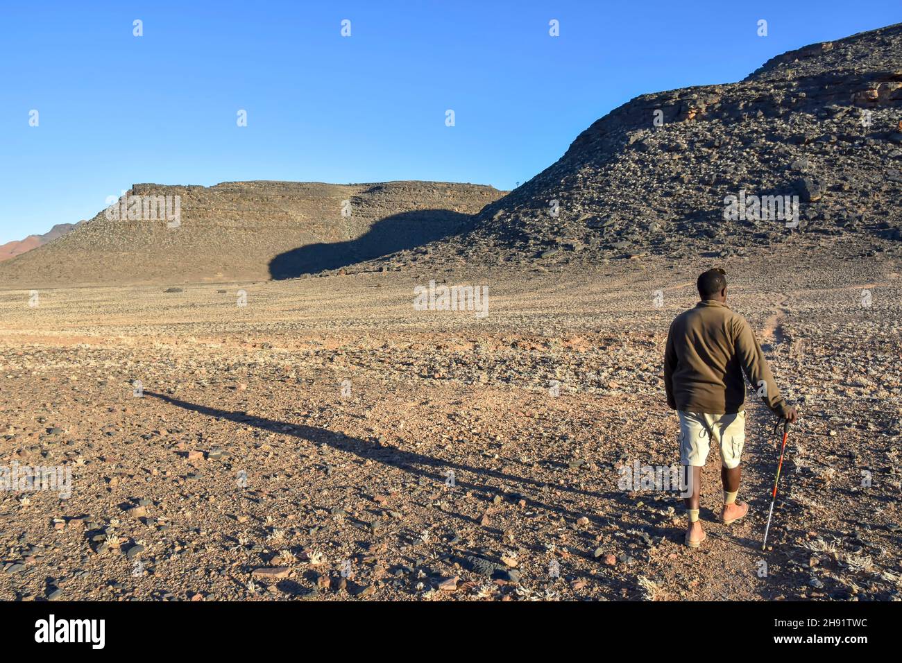 Un ranger del parco a piedi in maestose montagne vicino a valle del Sossusvlei in Namibia in Africa australe Foto Stock