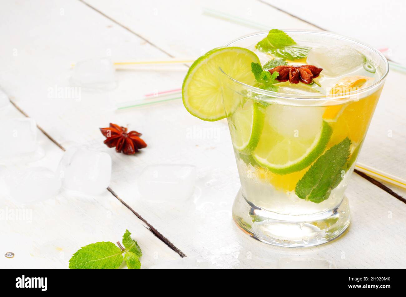 Lime e acqua di frutta arancione con ghiaccio e menta su tavola bianca Foto Stock